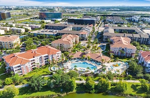 Un hotel con piscina central, varias edificaciones y zonas verdes circundantes.