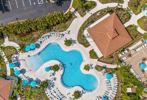 Vista aérea de un resort con una gran piscina, tumbonas y una zona cubierta con techo de baldosas.