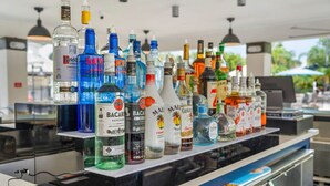 A bar with various bottles of alcohol, including Bacardi and Captain Morgan, and a laptop on the counter.