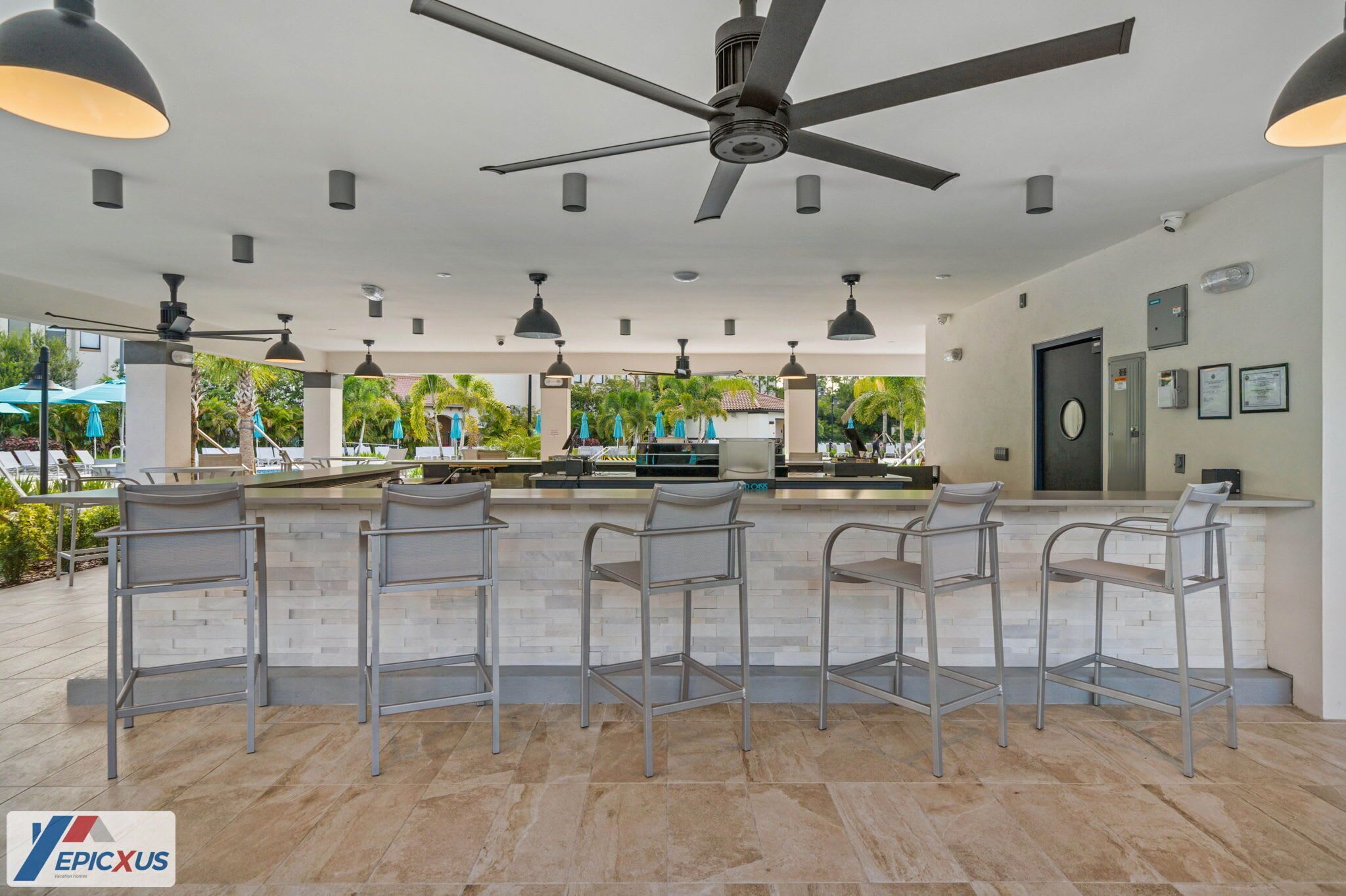 A modern bar area with a ceiling fan, multiple pendant lights, and bar stools.
