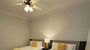A hotel room with two beds, a ceiling fan, and a nightstand with a lamp.