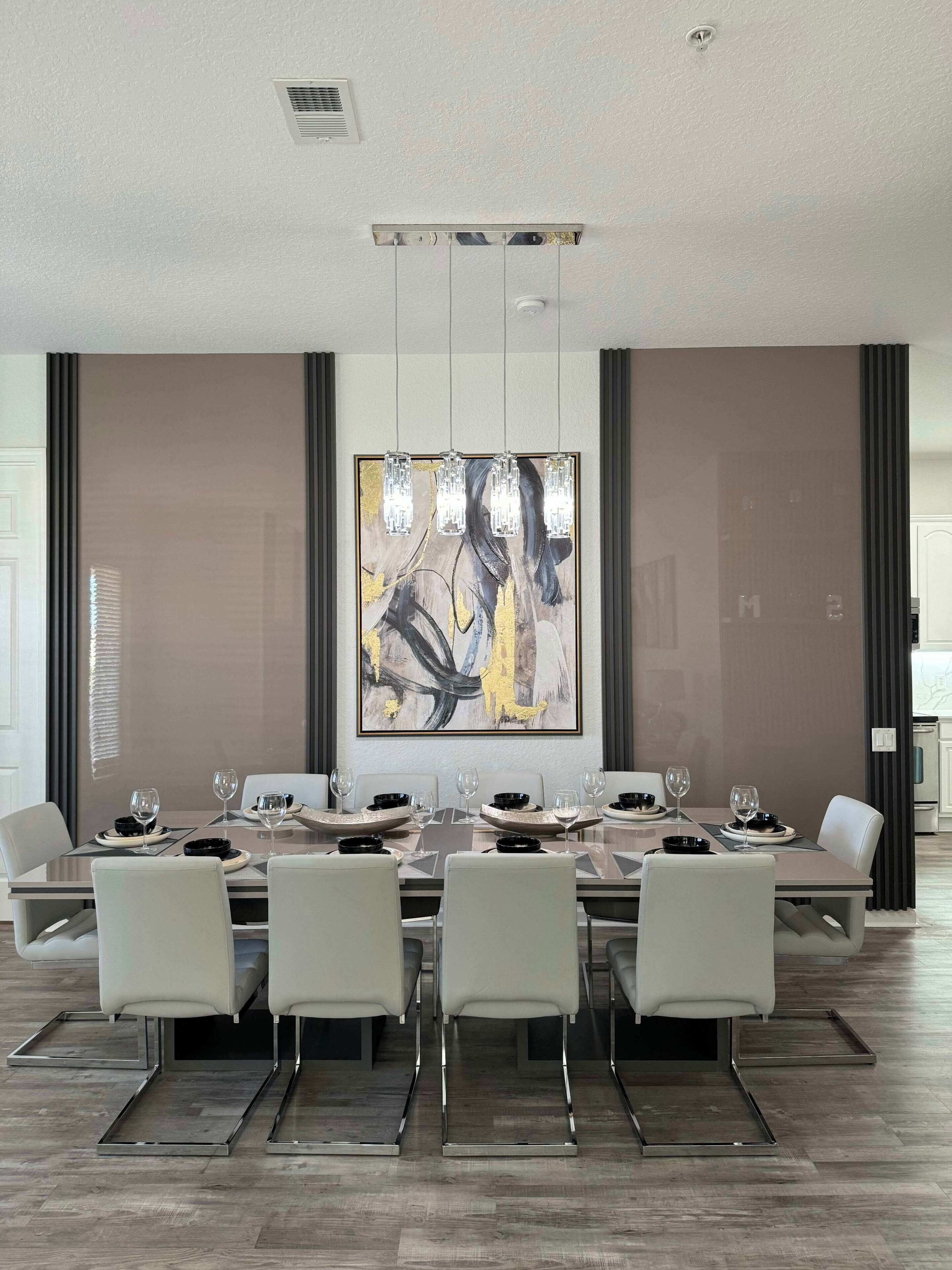A modern dining room with a long table, white chairs, and a large abstract painting on the wall.
