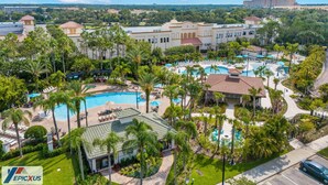 A resort with multiple swimming pools, palm trees, and a large building in the background.