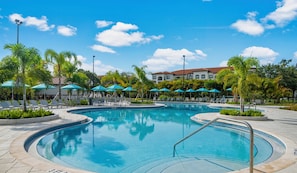 A swimming pool with lounge chairs and umbrellas, surrounded by palm trees and a building in the background. - The Epic 21 Vista Cay Resort Orlando Florida (Orlando)