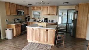 A modern kitchen with wooden cabinets, a central island, a microwave, a stove, and a refrigerator.