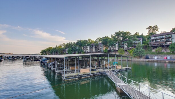 Eine Uferpromenade mit einem überdachten Sitzbereich, einer Brücke und Gebäuden im Hintergrund.