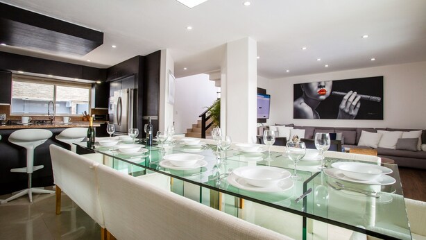 A modern kitchen with a glass dining table set for six, a built-in oven, and a large window. - Private Pool, Near Beach, Restaurants - Sleeps 11 (Puerto Vallarta)