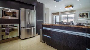 A modern kitchen with stainless steel appliances, a dark wood cabinet, and a large window providing a view of the desert landscape. - Private Pool, Near Beach, Restaurants - Sleeps 11 (Puerto Vallarta)