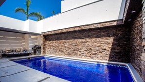 A swimming pool with a stone wall and a seating area with a grill. - Private Pool, Near Beach, Restaurants - Sleeps 11 (Puerto Vallarta)