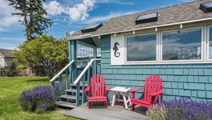 A house with a deck, two red Adirondack chairs, and a small table. - Twin View Cottage - King, Futon, jetted tub (Sequim)