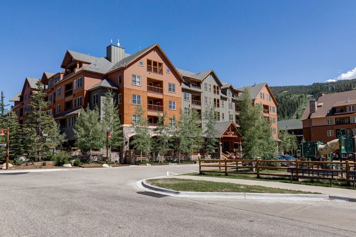 A multi-story hotel with a central courtyard, outdoor seating, and a playground.