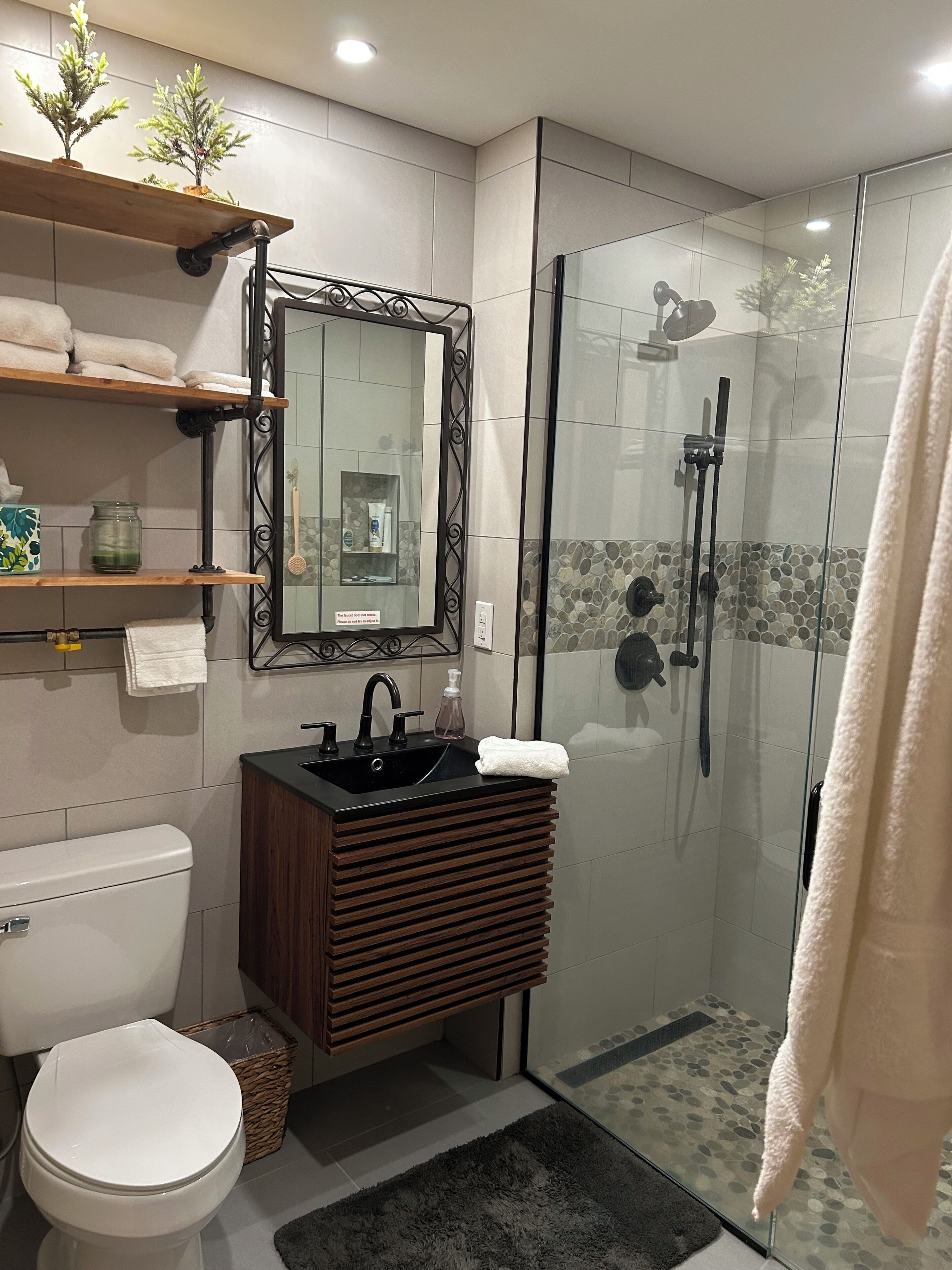 A modern bathroom with a toilet, sink, and glass-enclosed shower.