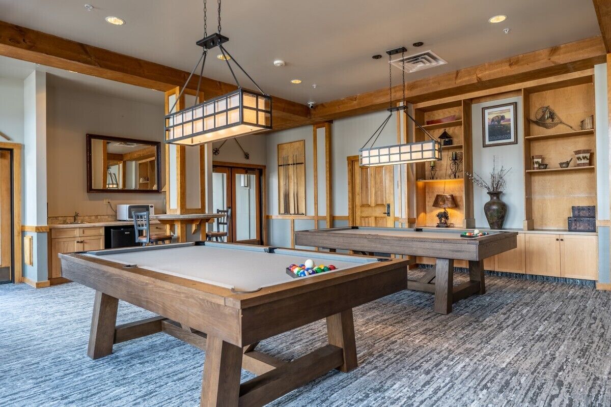 A pool table in a room with wooden beams and a carpeted floor.