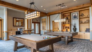 Une table de billard dans une pièce avec des poutres en bois et un sol recouvert de moquette.