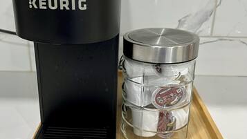 A Keurig coffee maker and a glass carafe with a lid on a wooden tray.