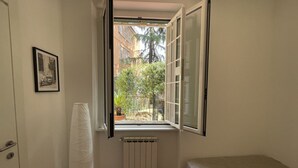 A small room with a single bed, a radiator, a window with an open shutter, and a framed picture on the wall. - La Dolce VIta - The Secret Terrace (Roma)