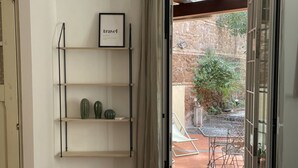 A doorway leading to an outdoor patio with a stone wall, a cactus, and a metal table and chair set. - La Dolce VIta - The Secret Terrace (Roma)