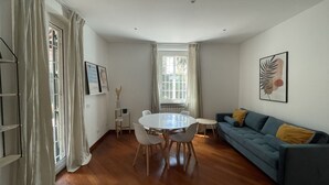 A modern living room with a round dining table, a sofa, and a window with curtains. - La Dolce VIta - The Secret Terrace (Roma)