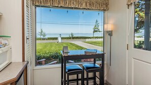 Ein Zimmer mit großem Fenster und Aussicht auf eine reizvolle Landschaft, einem kleinen Tisch mit Stühlen und einer Lampe.