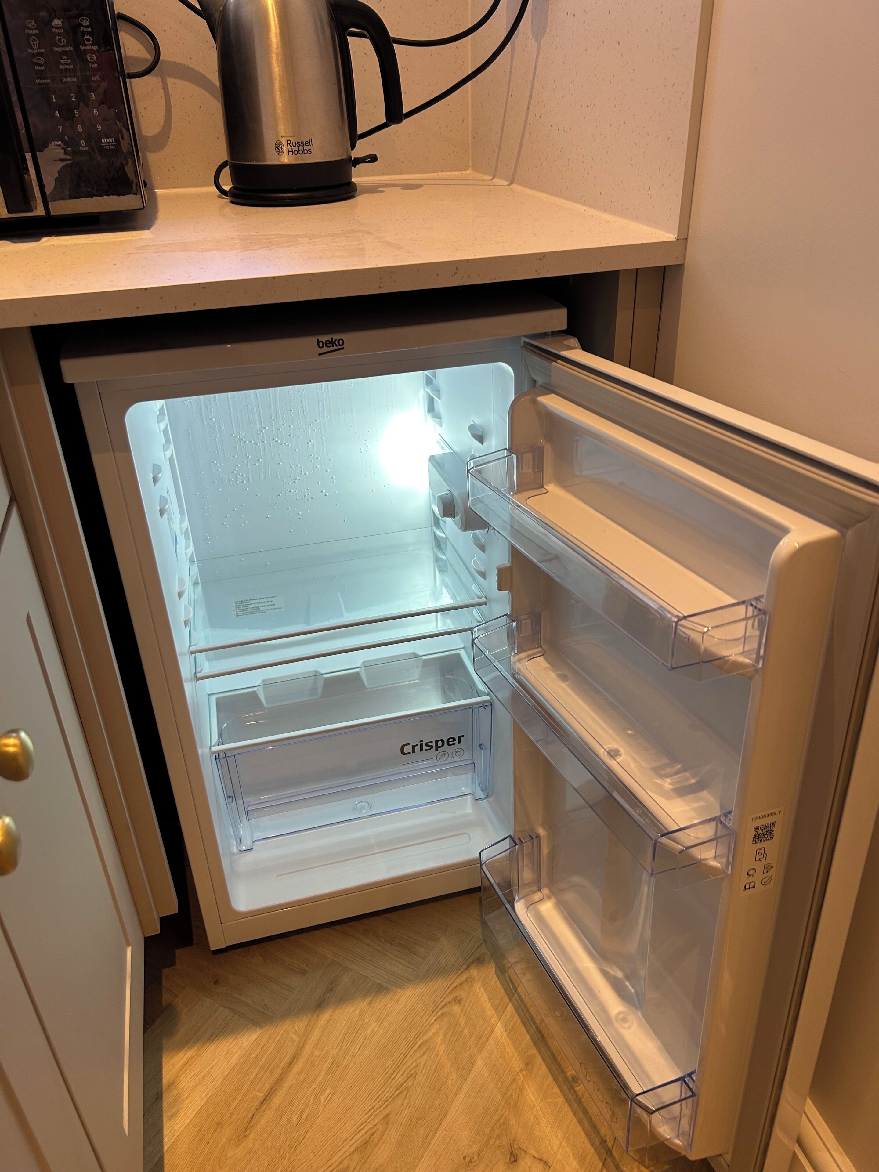 A refrigerator with a clear interior, a kettle on top, and a control panel.
