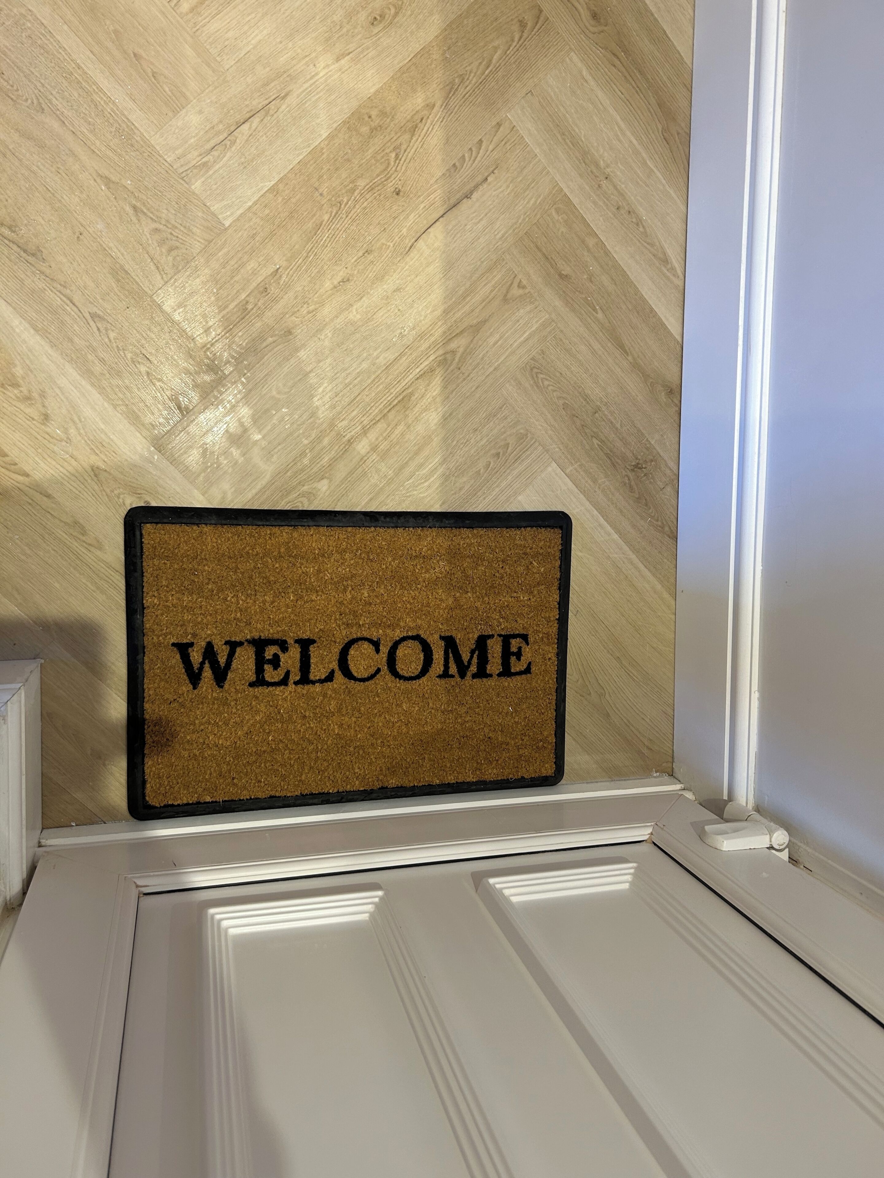 Eine Fußmatte mit der Aufschrift 'WELCOME' auf einem Holzboden.
