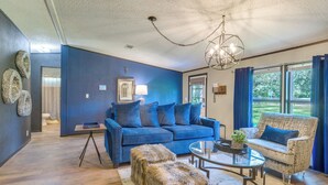 A modern living room with a blue sofa, a patterned armchair, a glass coffee table, and a rustic ottoman. - Pet-Friendly Ocala Vacation Rental w/ Patio! (Ocala)