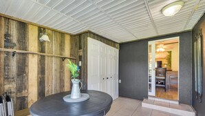 A dining area with a round table, a pitcher with flowers, and a wooden wall. - Pet-Friendly Ocala Vacation Rental w/ Patio! (Ocala)