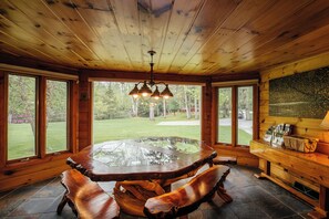 A wooden dining table with benches, large windows, and a chandelier.