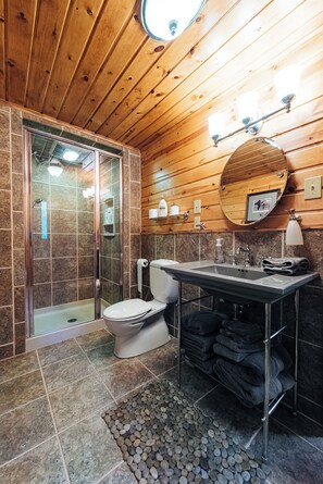 A bathroom with a glass-enclosed shower, a toilet, a sink with a mirror, and a towel rack.