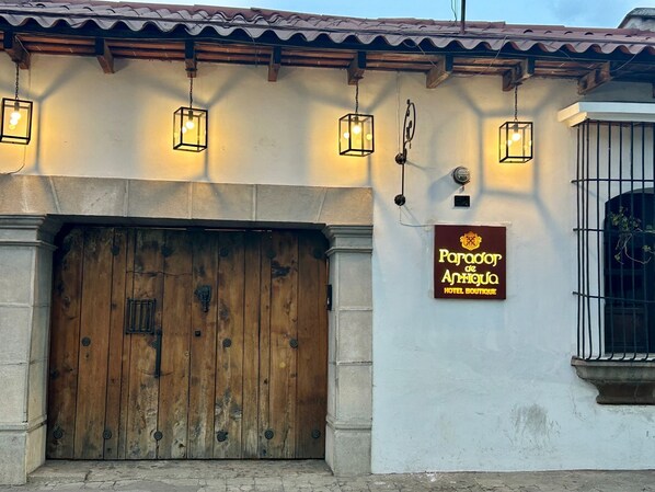 A hotel entrance with a wooden door, hanging lanterns, and a sign for 'Paradox de Annique Hotel Boutique'. - Parador de Antigua (Antigua Guatemala)