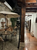Un patio al aire libre con una mesa, sillas, un muro de piedra y un farol colgante.