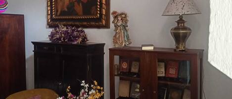 Una sala de estar con un cuadro grande enmarco, una pequeña estatua, una lámpara y dos sofás.