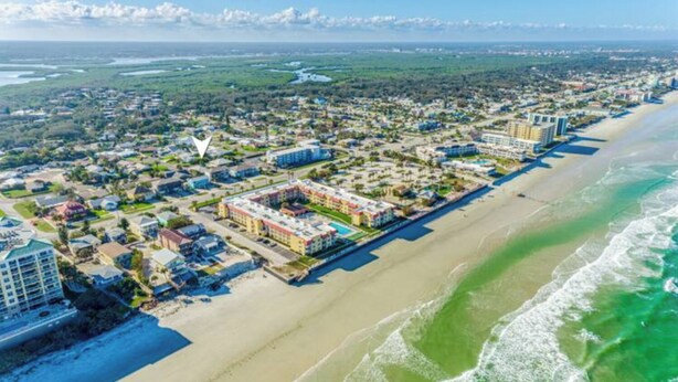 An aerial view of a coastal resort with beachfront properties, a marina, and a large hotel complex. - Peaceful beachside rental (New Smyrna Beach)