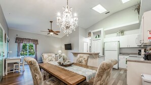 A dining area with a wooden table, floral upholstered chairs, a chandelier, and a ceiling fan. - Peaceful beachside rental (New Smyrna Beach)
