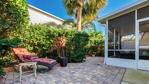 A patio area with a sun lounger, a small table, and a covered seating area. - Peaceful beachside rental (New Smyrna Beach)