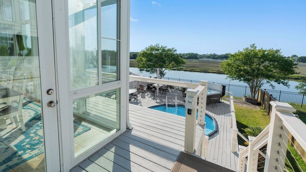A deck with a pool, outdoor furniture, and a view of a lake. - Marsh front home 10 min to beach and downtown- pet friendly! (Charleston)