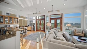 A spacious living area with a large sofa, a dining table, and a kitchen area with granite countertops. - Marsh front home 10 min to beach and downtown- pet friendly! (Charleston)