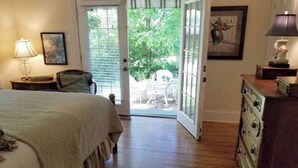 Une chambre à coucher comprenant un lit, une commode, une lampe et une porte donnant sur une terrasse.