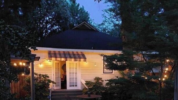A cozy house with a porch, a small garden, and a gravel path leading to the entrance.