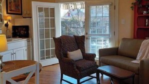 A living room with a patterned armchair, a sofa, a wooden coffee table, and a ceiling fan.