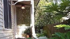 A house with a porch, a potted plant, and a wooden fence.