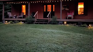 Eine Holzjagdhaus mit Veranda, Sitzgelegenheit im Freien und Lichterketten.