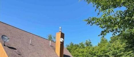 Una cabaña de madera de dos pisos con un porche cubierto y una chimenea.