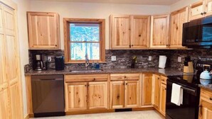 Eine moderne Küche mit Holzausstattung, einer Steinrückwand und einem schwarzen Backofen.