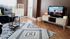 Una sala de estar con televisión, un sofá, una mesa de centro y una alfombra estampada.