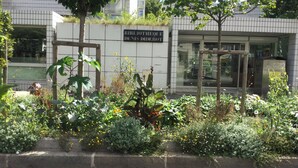 Un edificio con un letrero que dice "BIBLIOTHEQUE DENIS DIDEROT", rodeado de un jardín con diversas plantas y flores.