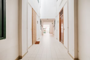 A corridor with white tiled floors, wooden doors, and a green gate in the distance. - GuestHost - Cozy apartment of about 55 square meters, able to accommodate up to 6 people, located on the 2nd floor of a building (NO LIFT). The apartment is located in a strategic area as it is only 180 meters from the station, 800 meters from the histor (Trapani)