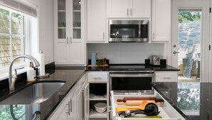 Una cocina moderna con armarios blancos, un lavamanos de acero inoxidable y un microondas.