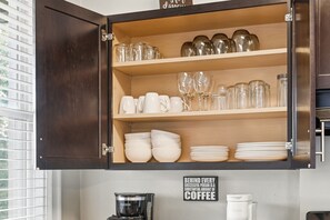 Un meuble de cuisine doté d’étagères où sont rangés des verres, des bols et des assiettes.