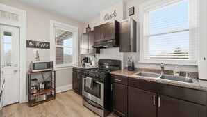 A modern kitchen with stainless steel appliances, dark cabinetry, and a granite countertop.